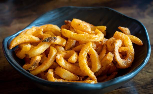 istock Blue bowl filled with freshly made curly fries placed on a table. 1486023909