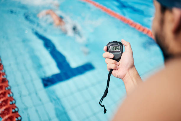 istock Sports, swimming and coach with a timer for training, exercise or a extreme sport competition. Fitness, pool and athlete or swimmer doing a cardio workout or practice with a mentor with a watch. 1486027343