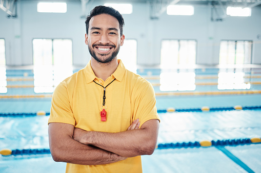 Portrait, proud and coach at a swimming pool for training, exercise and practice at indoor center. Face, happy and personal trainer ready for teaching, swim and athletic guidance, smile and excited