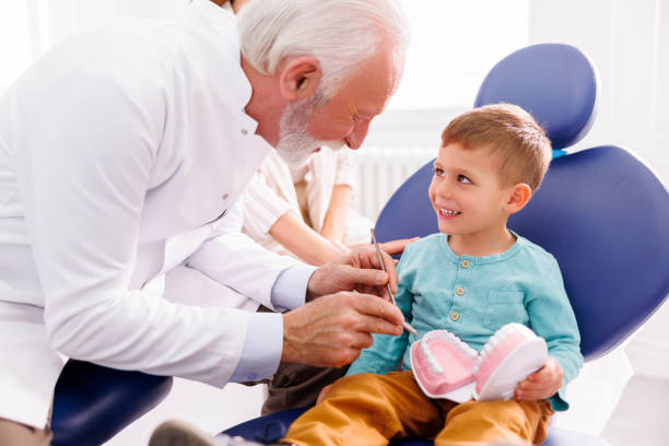 istock Dentist showing checkup procedure on plastic jaw model to child patient 1486030045