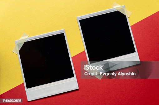 istock Download Blank photo frames template on red and yellow background. Blank square photo frames with tape on wall copy space 1486030815