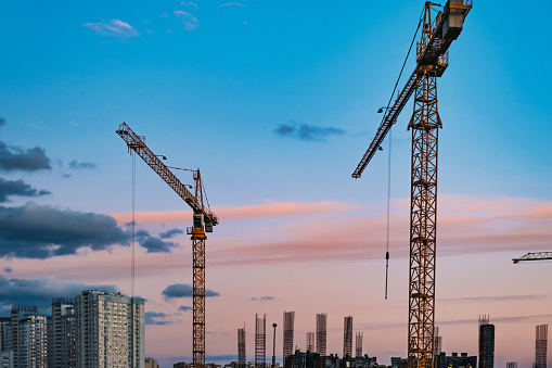 Large construction site with cranes working on a building complex, with sunset sky. download image