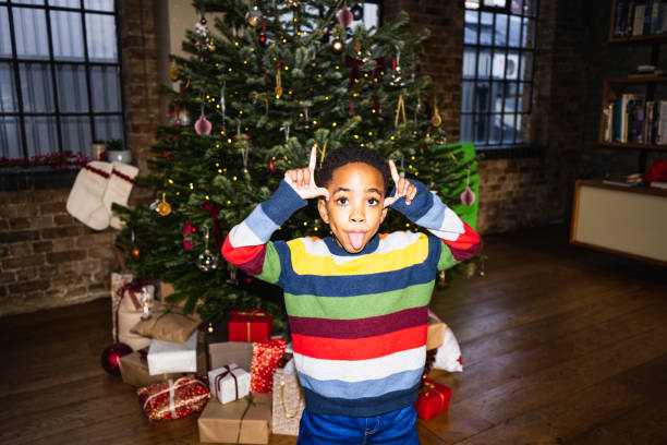 Front view of 6 year old child in striped sweater looking at camera, gesturing, and sticking out his tongue. On-camera flash, retro-style photographic effect.