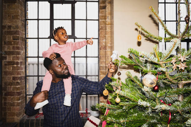 Father and young daughter admiring Christmas tree decorations
