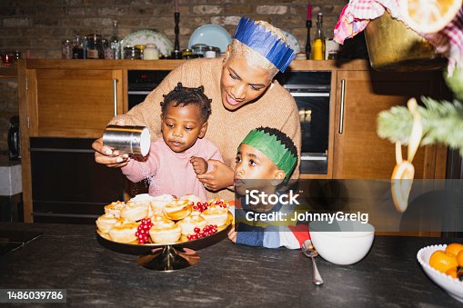 istock Mother and children sprinkling icing sugar on mince pies 1486039786