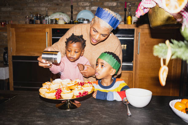 mãe e filhos polvilhando açúcar de confeiteiro em tortas picadas - celebratory holiday flash - fotografias e filmes do acervo