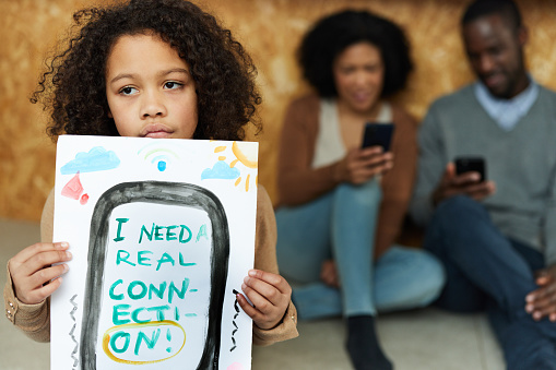 Sad African American girl holding a drawing with a concept of real connection instead of virtual one.