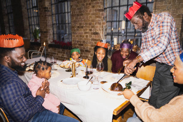 senior black man igniting christmas pudding at dining table - pre teen boy flash imagens e fotografias de stock