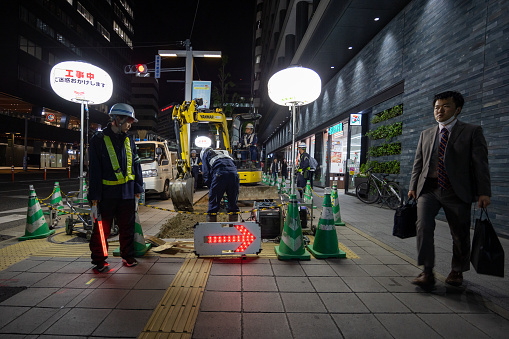 Fukuoka, Japan - April 21, 2023 : Workers repair part of the road at night in Fukuoka, Kyushu, Japan.