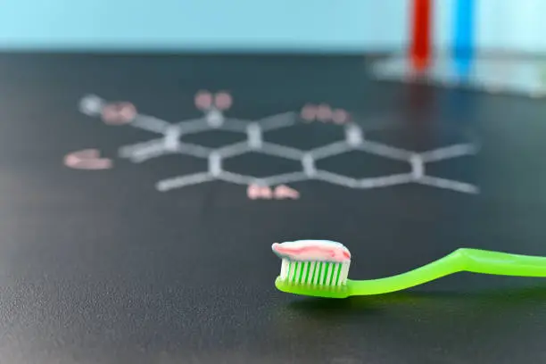 Toothpaste applied to the toothbrush on a background of the chemical formula.