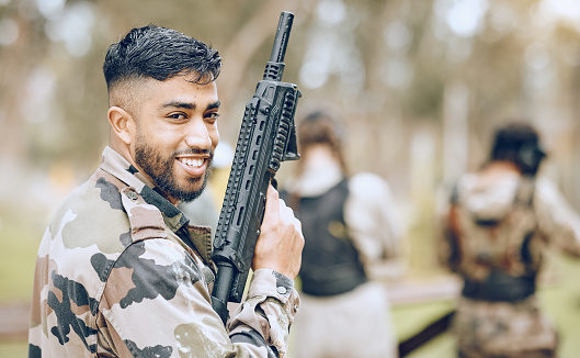 Paintball gun, man and portrait with smile, camouflage clothes and excited to start military combat game. Army training, warfare games and adventure for workout, shooting and challenge with friends