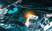 Auto mechanic checking engine system with OBD2 wireless scanning tool and car information showing on screen interface