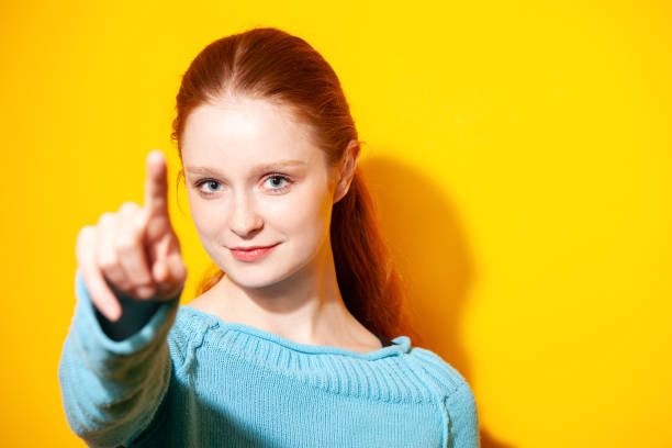 Young redhead white woman pressing virtual button. touches with index finger