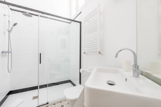 istock Bathroom with shower cabin with screen with black details, white marble tiling, white electric towel rail and chrome accessories 1486050096