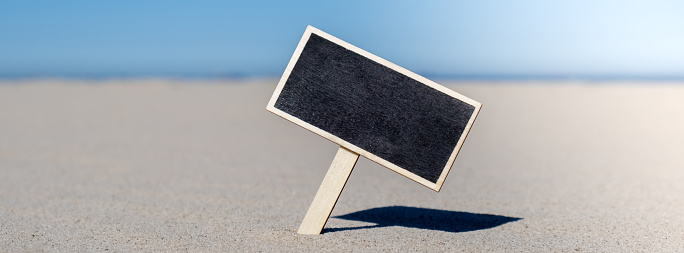 Empty blackboard frame board with copy space for your text or design displays on sandy beach. Summer vacation and holiday business travel concept. Template Mock up for sale promotion advertisement. Travelling, trip Chalkboard
