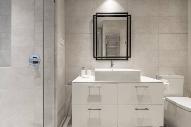 istock Bathroom with mirror with black metal structure, white porcelain sink, glossy white drawer unit, marble tiles and chrome electric towel rail 1486050245