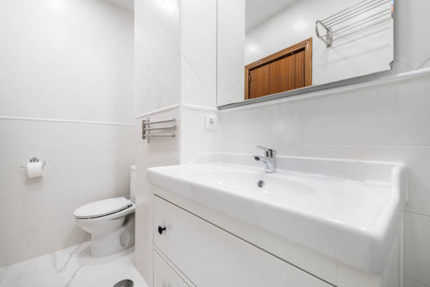 istock White porcelain sink with white wood cabinet, frameless mirror and white tile 1486050255