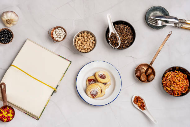 istock Still life with tea biscuits, chestnuts and chickpeas, cayenne pepper and spiced cloves with black and white beans, garlic and covered with a blank book 1486051150
