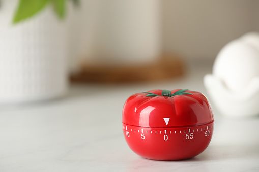 Kitchen timer in shape of tomato on white table. Space for text