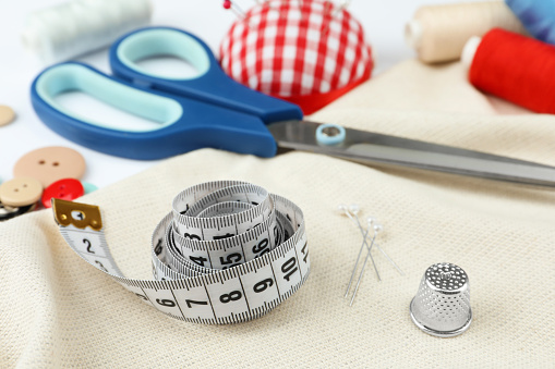 Different sewing accessories on white background, closeup
