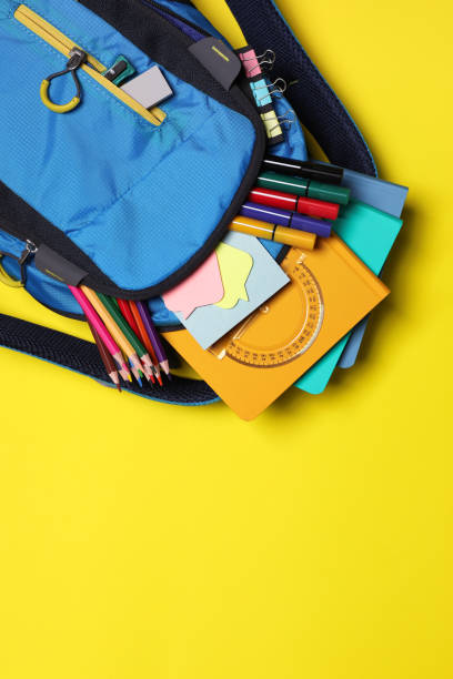 istock Backpack with school stationery on yellow background, top view. Space for text 1486051809