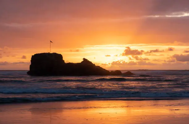 A dramatic sunset on Perranporth Beach in Cornwall, silhouetting the rocky landmark that is Chapel Rock.