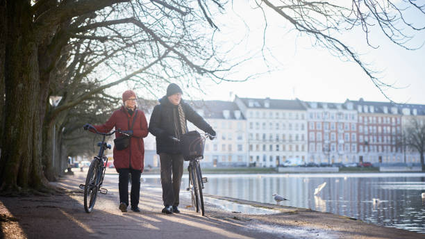 istock Smiling senior couple walking by a river with bikes in winter 1486052865