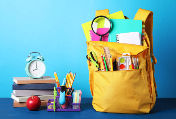 istock Yellow backpack and different school stationery on blue wooden table 1486052867