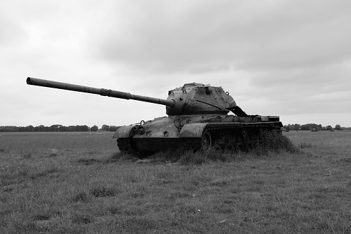 A grayscale shot of a tank situated in the center of a battlefield