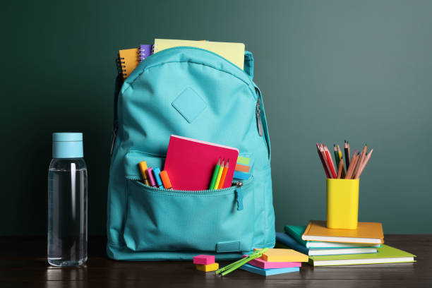 istock Backpack with different school stationery on white table near chalkboard 1486052987