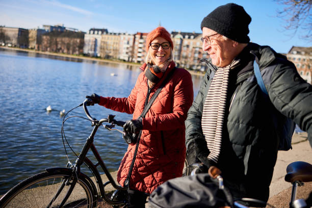 istock Senior couple with bikes smiling while walking on a river path in winter 1486053229