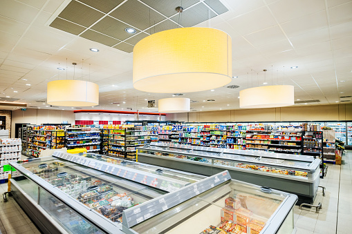 A large, modern supermarket with shelving filled with food items, and large freezers filled with food.