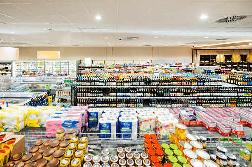 A supermarket with lots of well organised shelves filled with a variety of different canned, bottled and packaged produce.