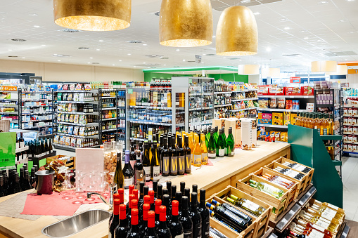 Some alcohol and food items on display in a well stocked, modern supermarket with no customers.