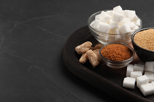 Different types of sugar on black table, closeup. Space for text