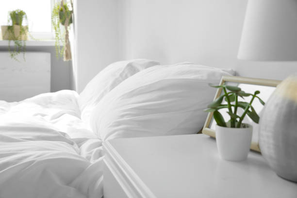 Large comfortable bed with soft pillows and blanket indoors