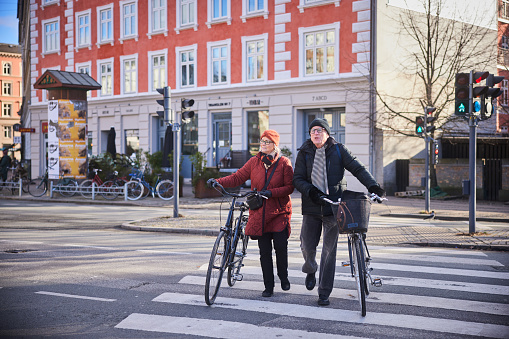 Senior couple with bicycles crossing a street in the city in the wintertime