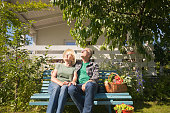 Senior couple sitting on bench in allotment during sunny day