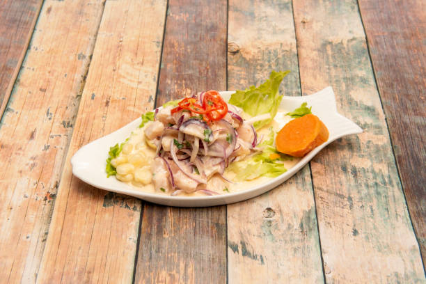 Peruvian corvina ceviche marinated with lime, onion, corn kernels, sweet potato and lettuce in a fish-shaped plate Peruvian corvina ceviche marinated with lime, onion, corn kernels, sweet potato and lettuce in a fish-shaped plate on wooden table raw croaker fish stock pictures, royalty-free photos & images