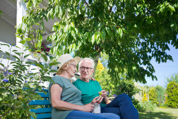istock Senior couple talking to each other while sitting on bench in back yard 1486060358