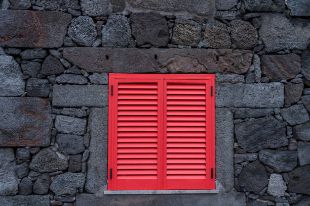 Small picturesque village, houses made of volcanic rocks, red window on the wall made of volcanic rocks. Cabrito, Pico island, Azores