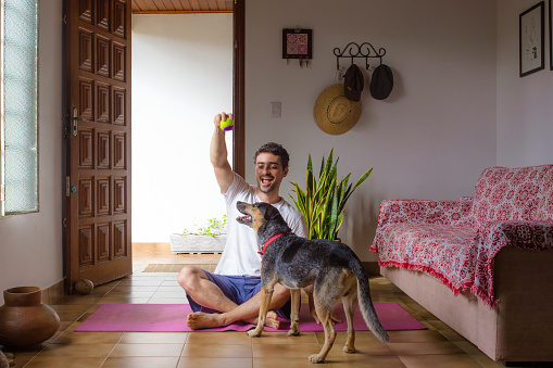 man plays with his dog sitting on the living room floor