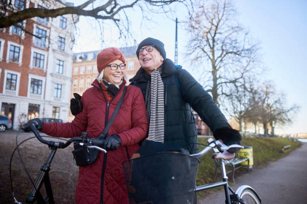 istock Laughing senior couple standing with their bikes on a park path in winter 1486067616