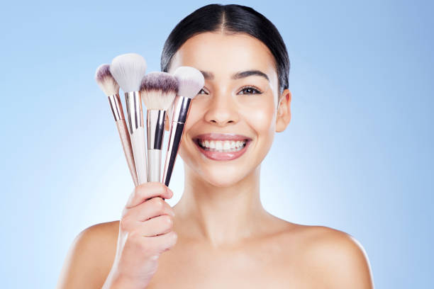 beauty brushes, makeup and portrait of woman with smile on blue background for cosmetics, powder and foundation. skincare, cosmetology and face of girl with brush for application, eyeshadow and salon - face powder make up blue eyeshadow imagens e fotografias de stock