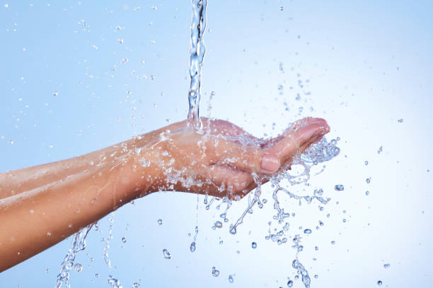 istock Hands, water splash and wash for skincare hygiene or hydration against a blue studio background. Closeup of hand with liquid drops, shower or washing for clean wellness or natural sustainability 1486069814