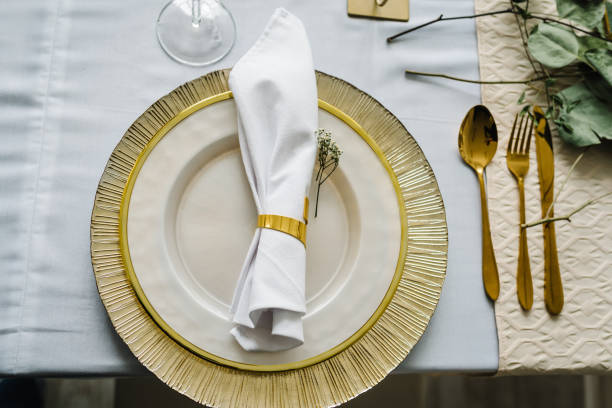 istock Table setup. Festive table setting with plate, golden cutlery set and eucalyptus leaves. Dinner table decorated for cozy fall holiday gathering in kitchen. Top view. Element for design. Closeup. 1486070209
