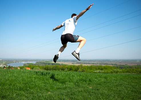 young man jumps, training in a beautiful natural environment, beautiful landscape, training for body and mental health
