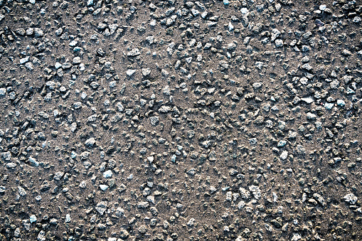 Close-up of a section of weathered road surface, with asphalt and gravel.