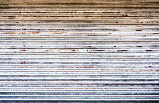 A large surface of rusting metal store shutter at a closed shop building.