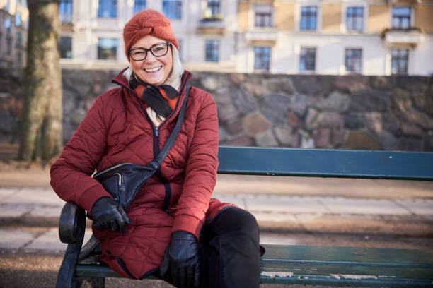 istock Senior woman laughing while sitting on a park bench in winter 1486073881